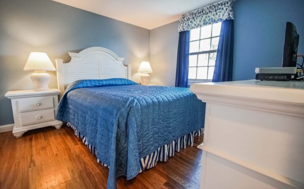 Photo of bedroom with queen bed, dresser and tv
